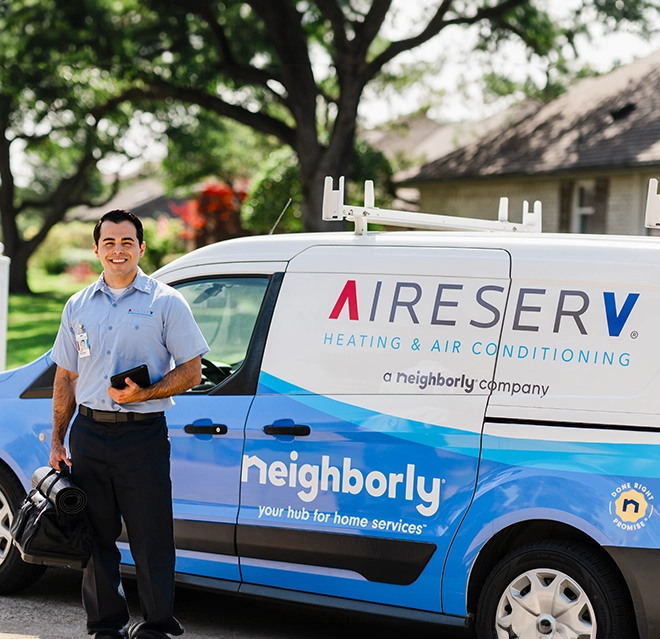 Aire Serv service professional with toolbag in front of branded van.