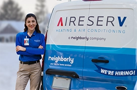 Female Aire Serv tech standing next to branded van.