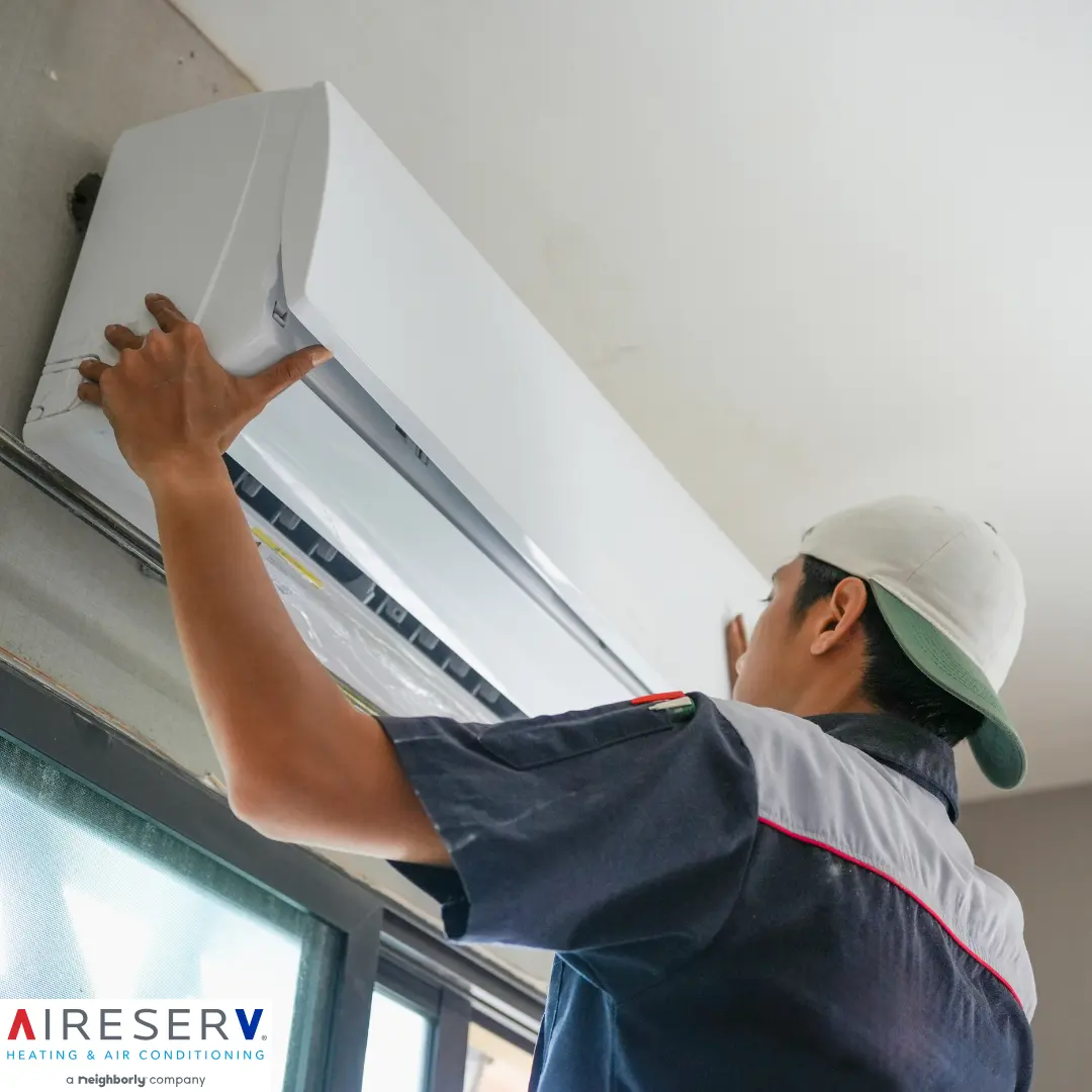 Aire Serv technician inspecting an outdoor AC condenser unit at a Wilmington, Delaware home at the end of summer.