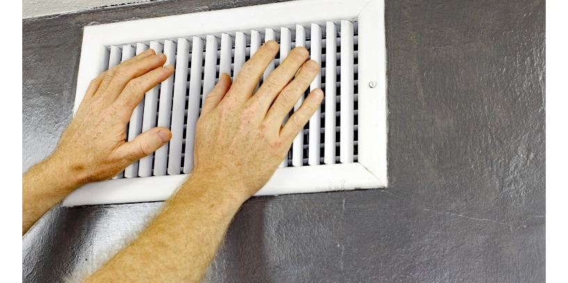 Homeowner testing their heating and cooling system by placing hand near vent