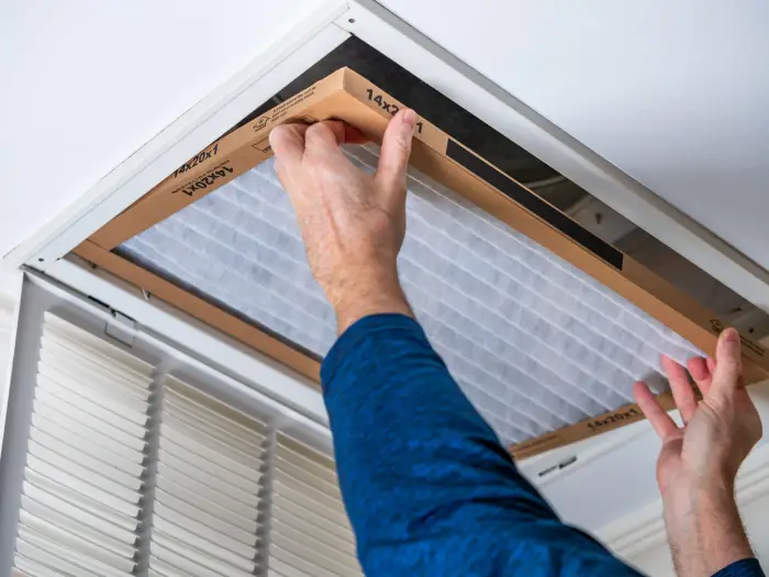 Air filter being installed into ceiling vent.