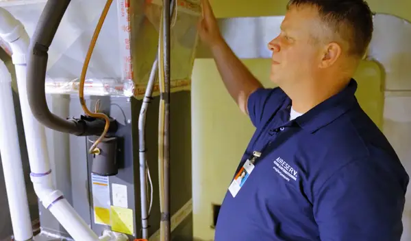Aire serv technician inspecting a HVAC unit