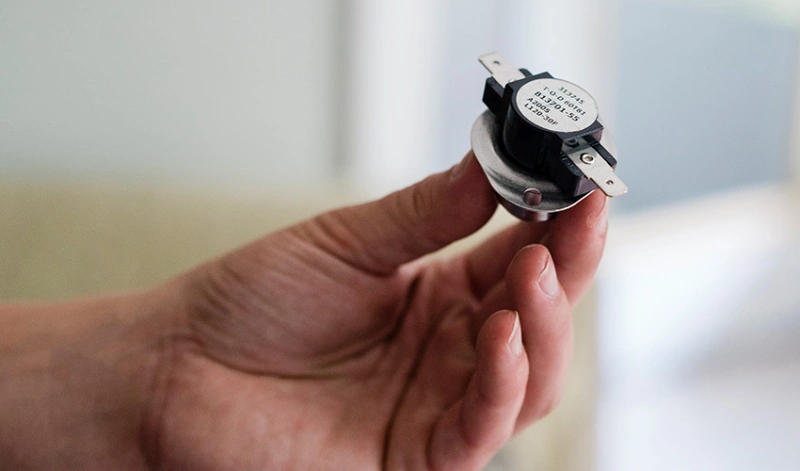 Hand holding a furnace limit switch
